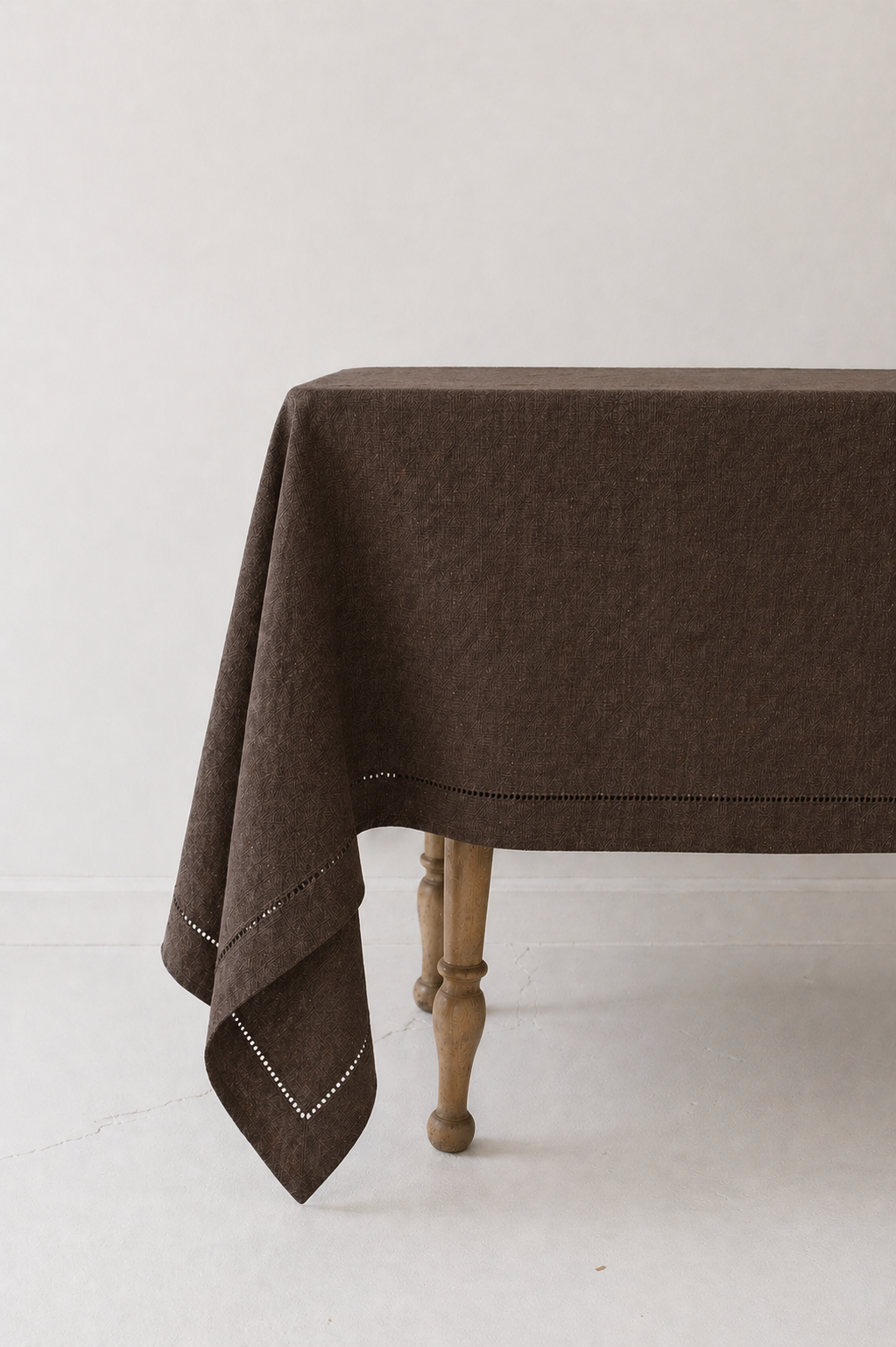 Brown linen tablecloth draped over a wooden table on a white background