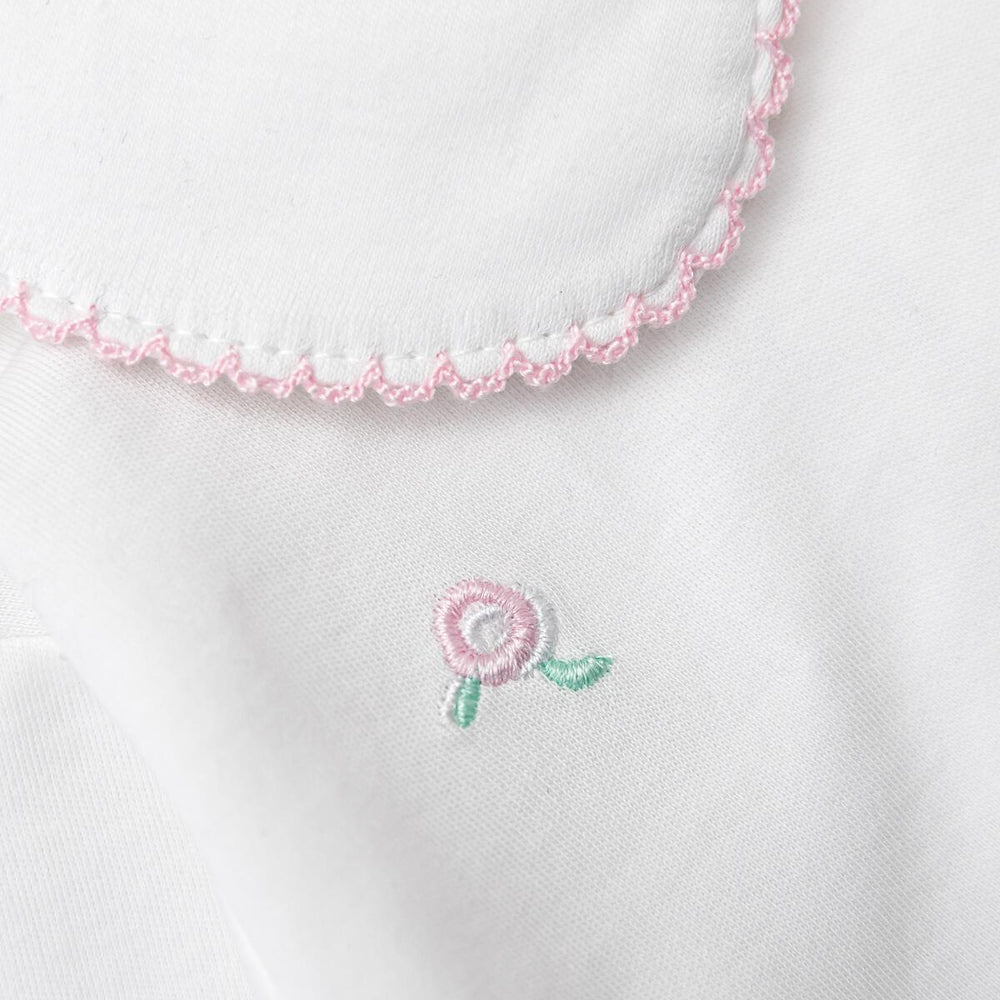 Close-up of embroidered pink flower design on a white fabric background
