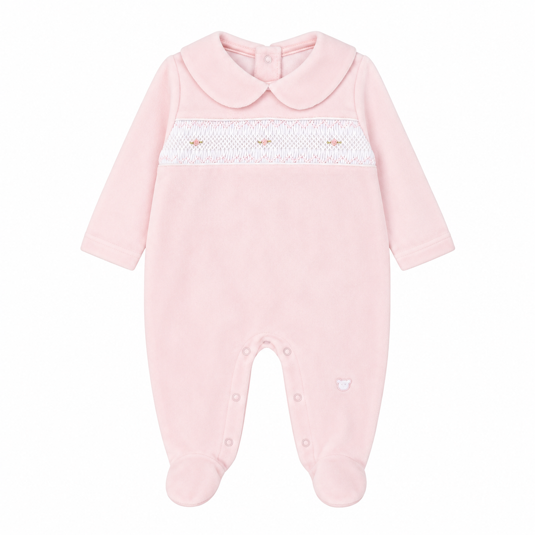 A light pink baby footed sleeper with a Peter Pan collar, long sleeves, and a white smocked chest band with tiny embroidered details.