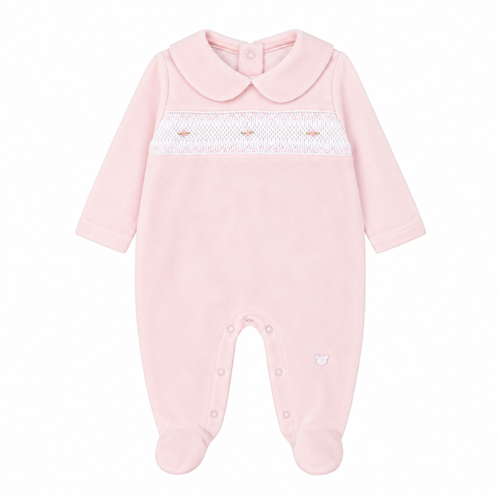 A light pink baby footed sleeper with a Peter Pan collar, long sleeves, and a white smocked chest band with tiny embroidered details.