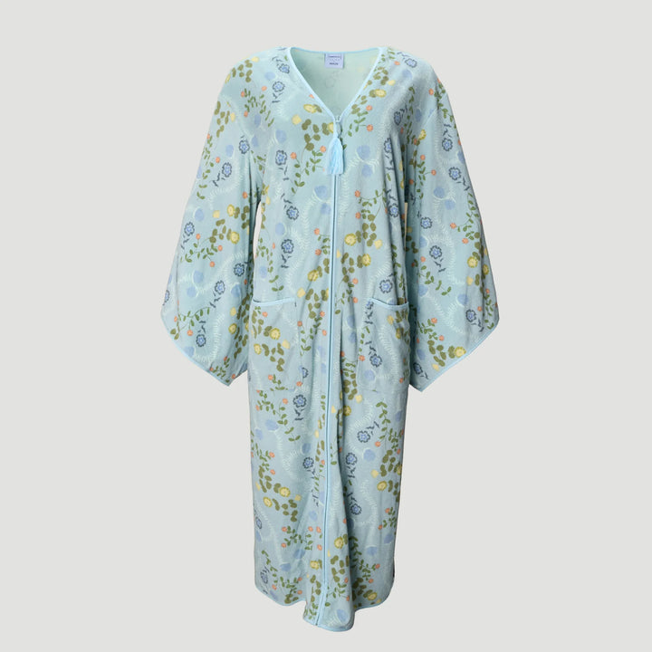 A light blue kaftan-style robe with a delicate floral and botanical print in green, yellow, and blue, featuring a V-neckline, front zipper, and side pockets, shown against a solid light gray background.