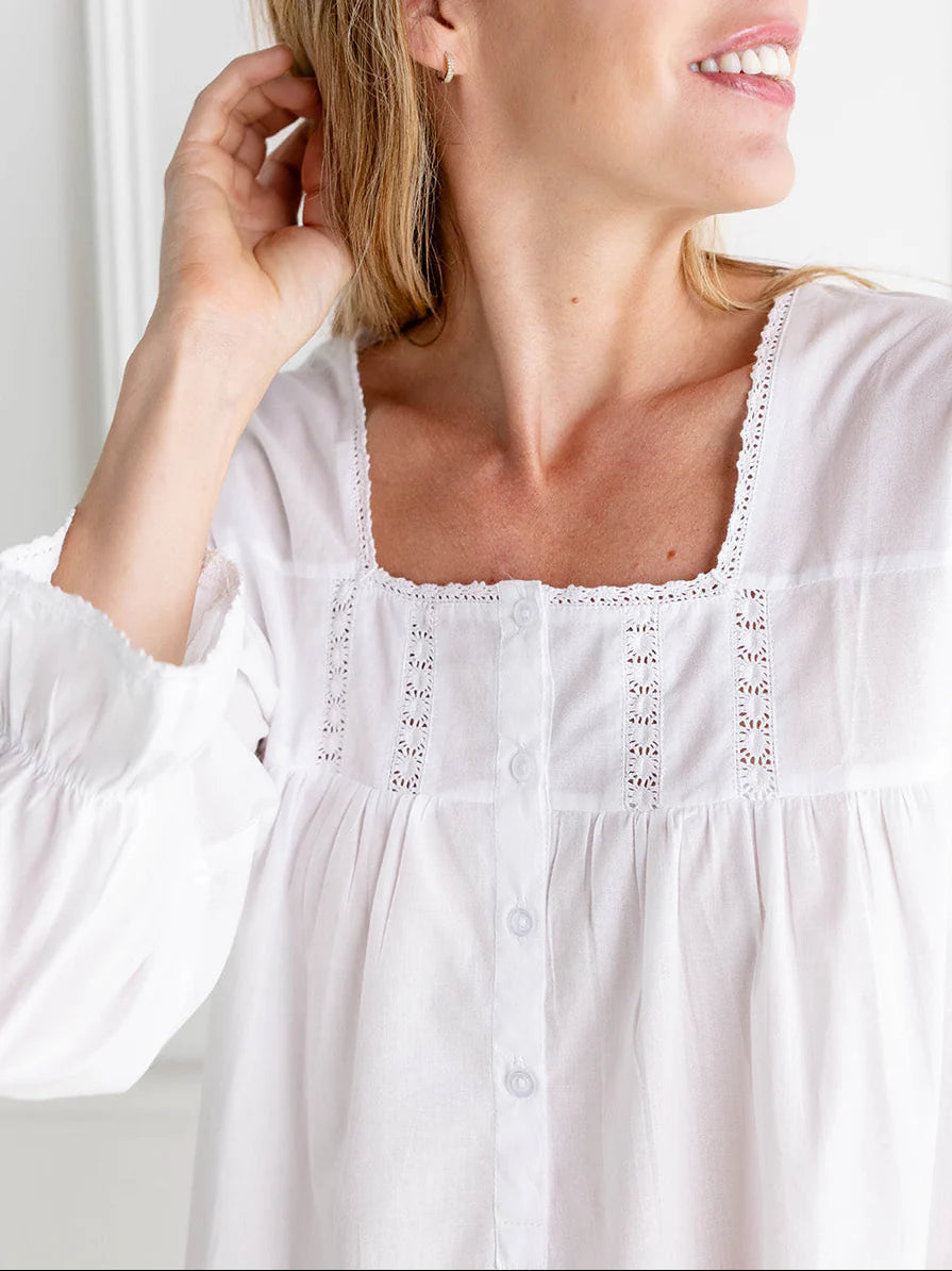 Close-up of a woman wearing a white blouse with intricate detailing.