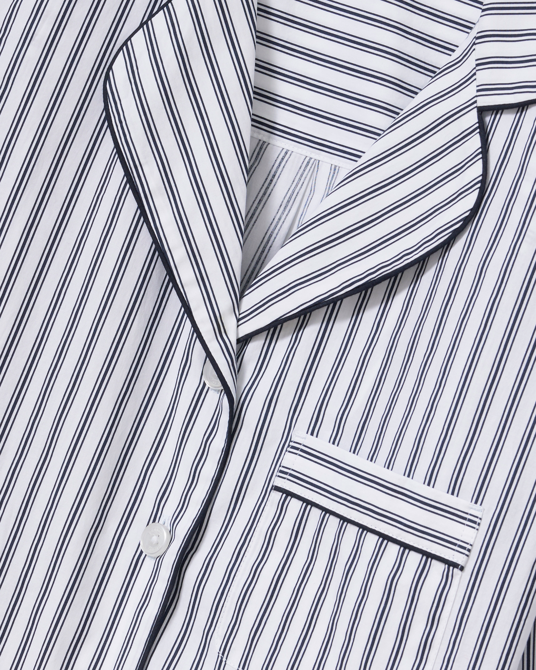 Close-up of a white collared shirt or pajama top with narrow navy vertical pinstripes and a matching collar.