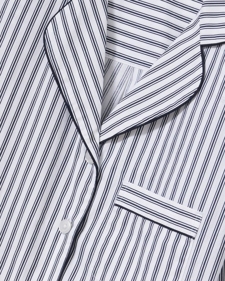 Close-up of a white collared shirt or pajama top with narrow navy vertical pinstripes and a matching collar.