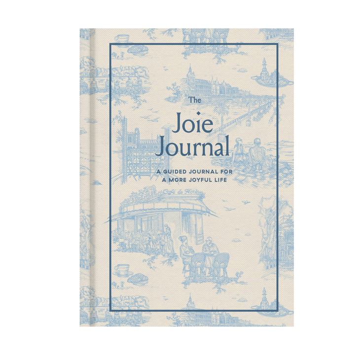 The Joie Journal, a guided journal with a cream-colored cover featuring a light blue toile de Jouy pattern and a central blue border with the title.