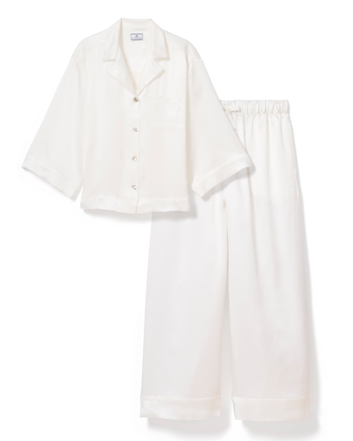 An off-white two-piece pajama set consisting of a short-sleeve button-front shirt and matching wide-leg pants, laid flat on a white background.
