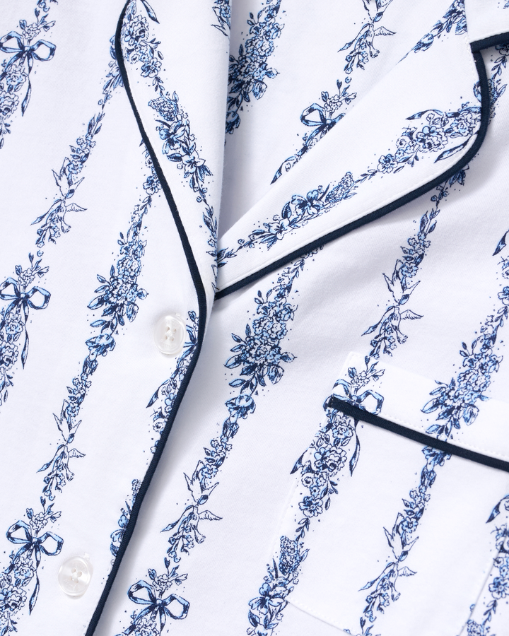 Close-up of a white pajama shirt with a blue floral toile pattern and black piping trim.