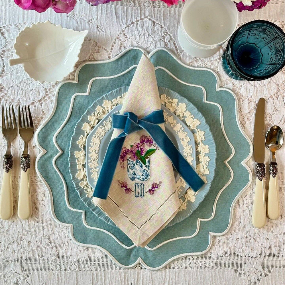 Elegant table setting with decorative plates, napkin, and cutlery on a lace tablecloth.