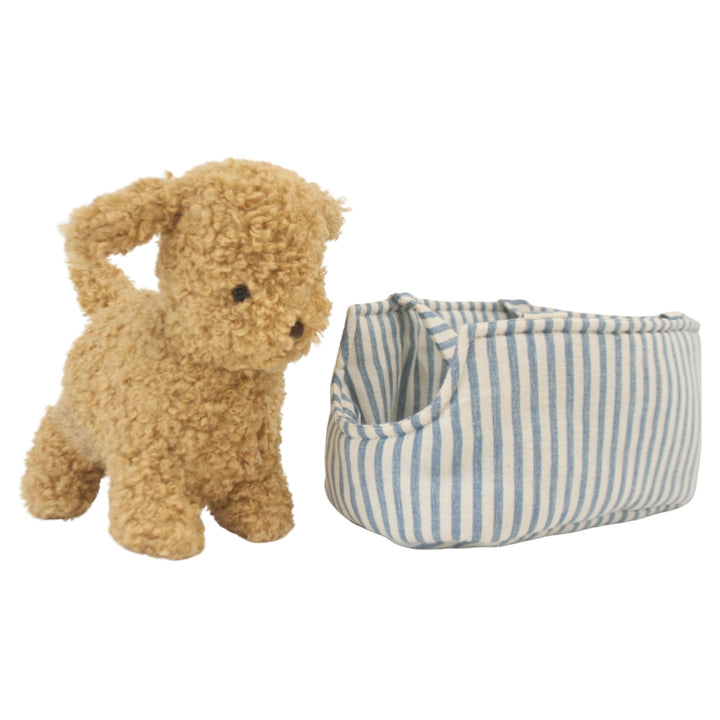 Stuffed dog toy next to a striped fabric basket on a white background