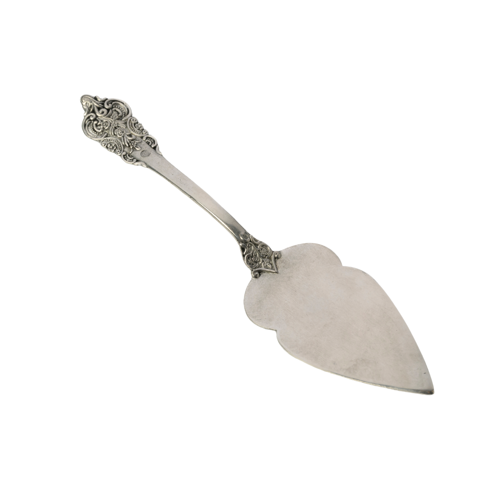 Silver cake server with decorative handle on a white background