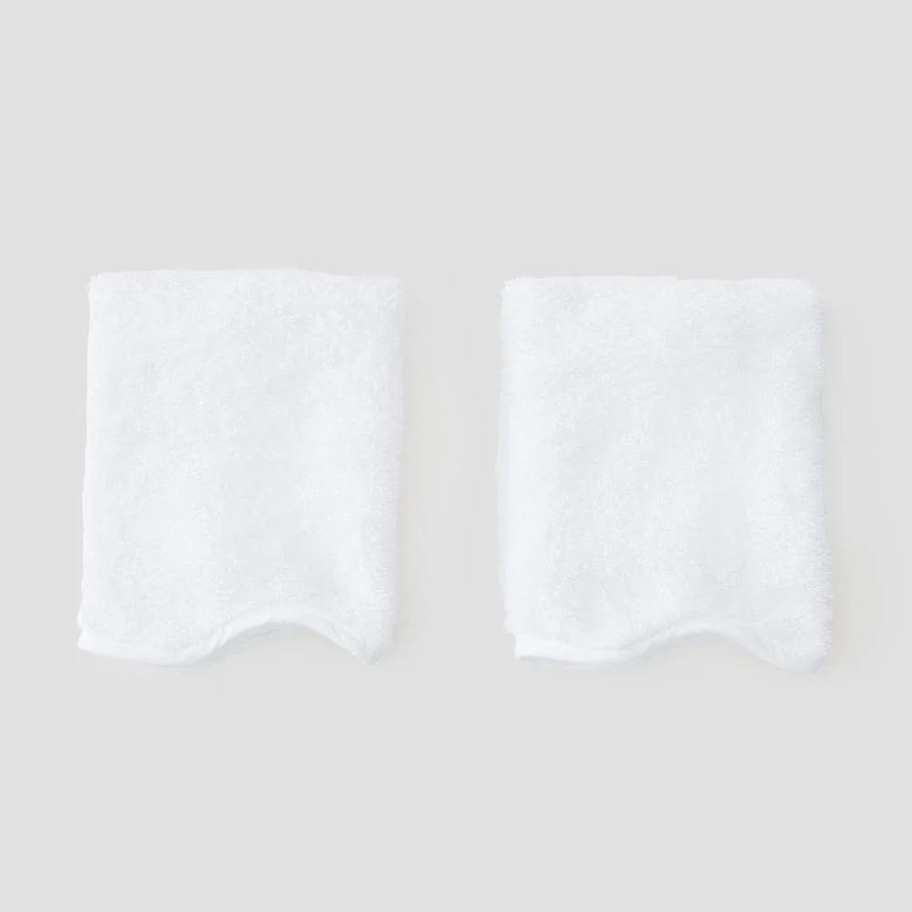 Two folded white towels with scalloped edges, displayed side-by-side on a light gray background.