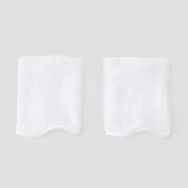 Two folded white towels with scalloped edges, displayed side-by-side on a light gray background.