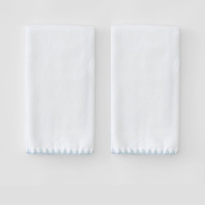 Two folded powder towels with blue stitched shell hem