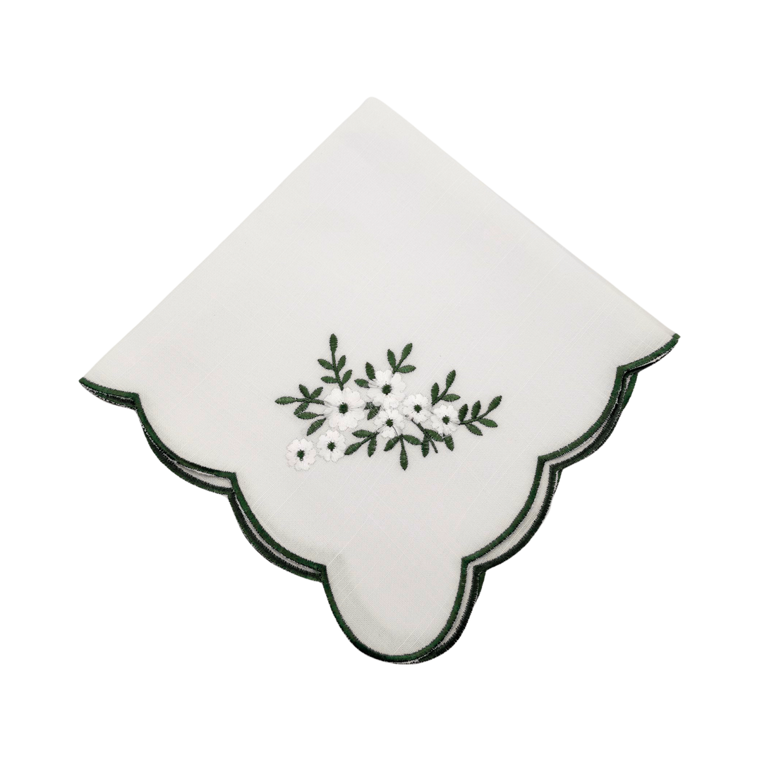 White napkin with green floral embroidery on a white background