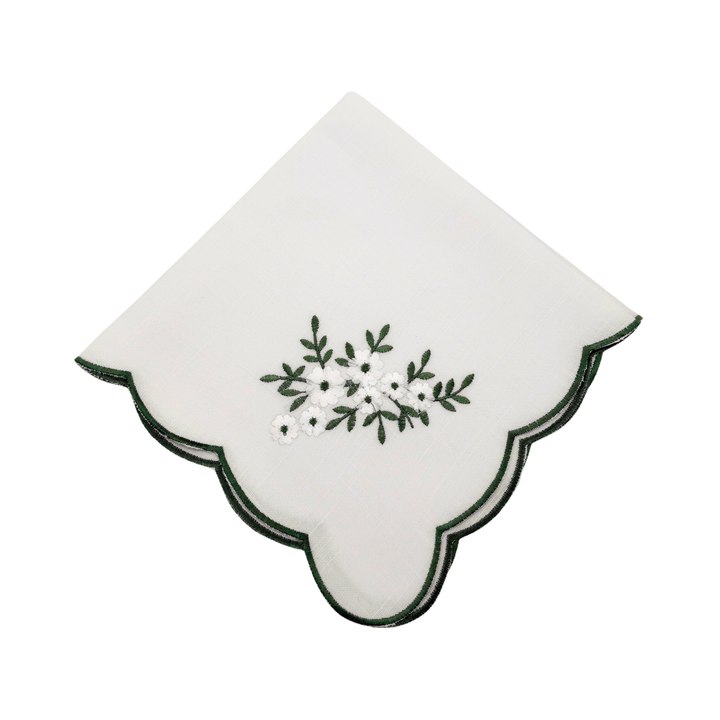 White napkin with green floral embroidery on a white background