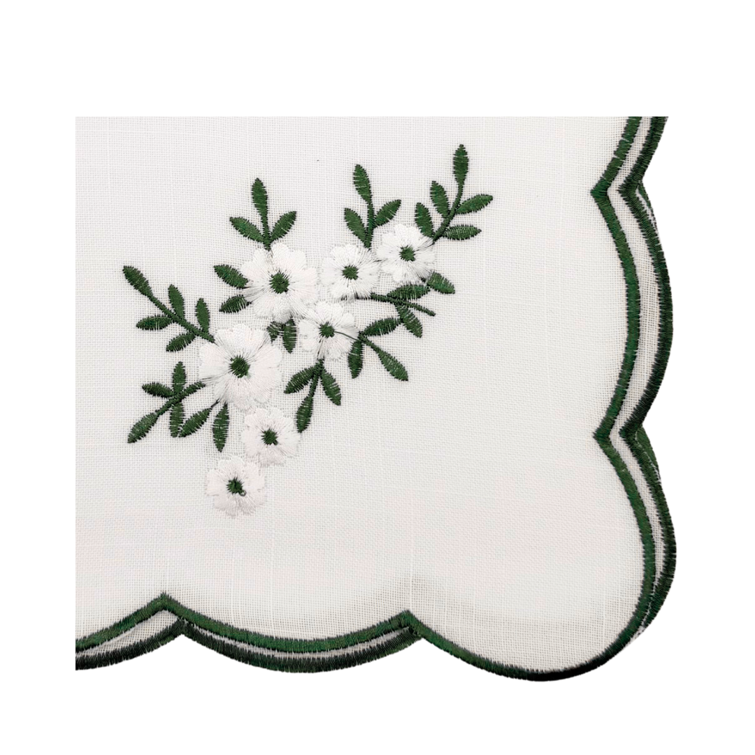 Embroidered design with green leaves and white flowers on a scalloped edge fabric