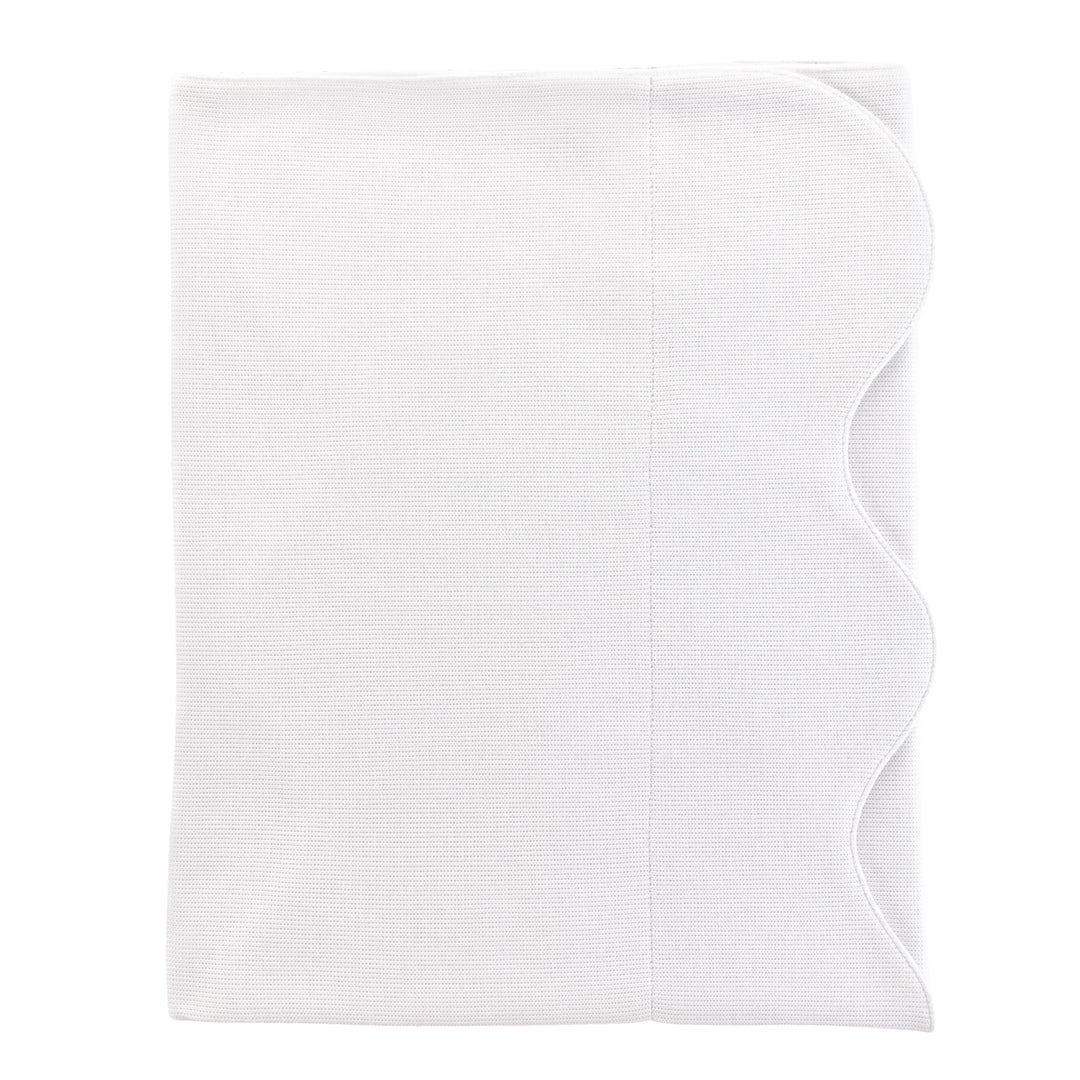 A folded white baby blanket with scalloped edge