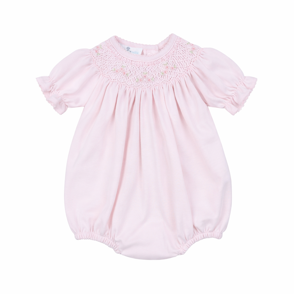 Pink baby romper with smocked bodice on a white background