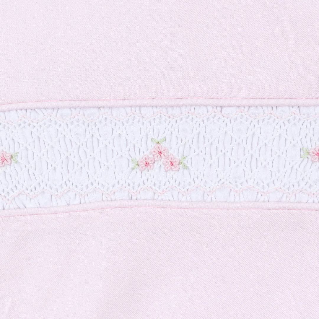 Close up of pink baby footie showcasing smocking and embroidered flowers