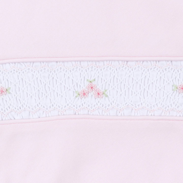 Close up of pink baby footie showcasing smocking and embroidered flowers