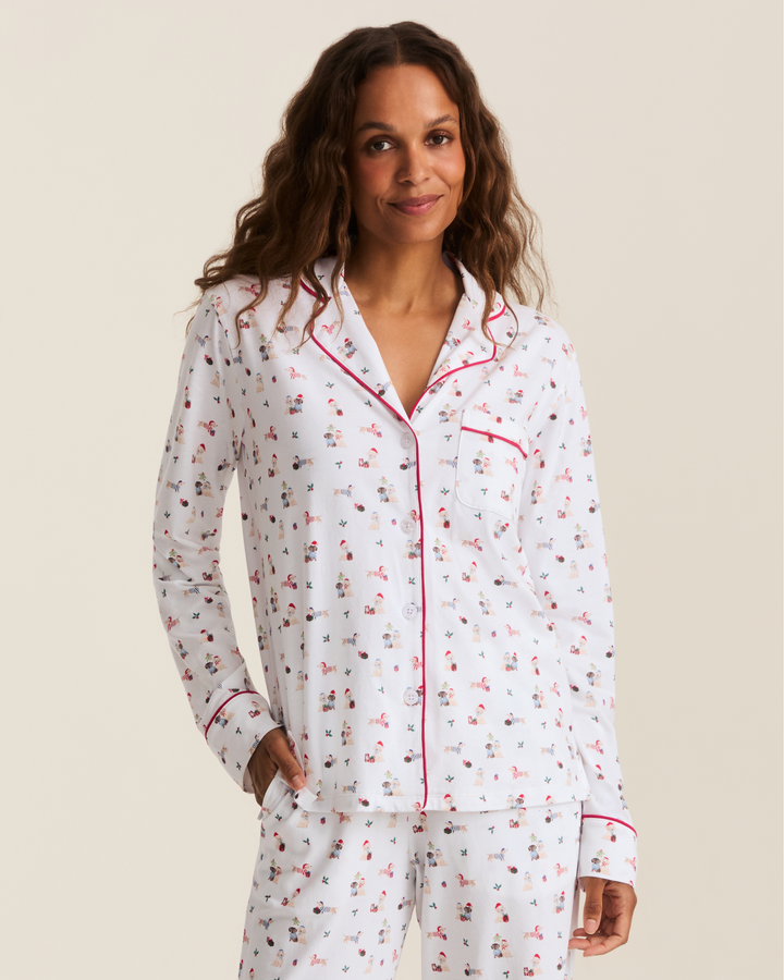 A woman modeling a two-piece pajama set with a white background and a whimsical puppy print.