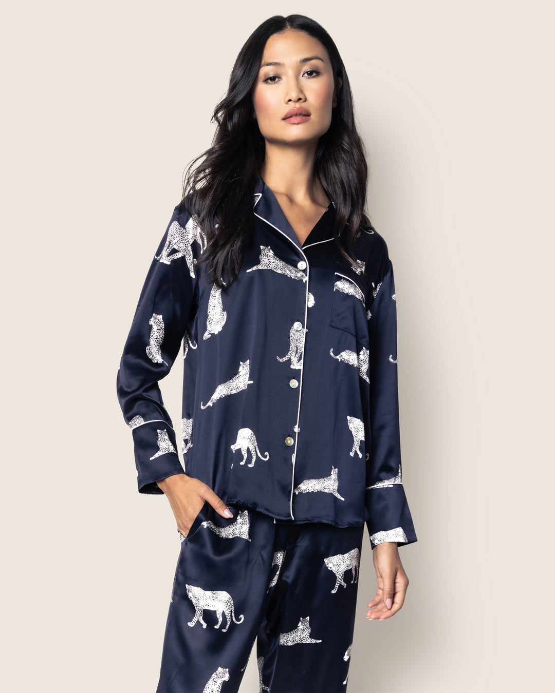 Woman wearing navy pajamas with white animal prints on a plain background