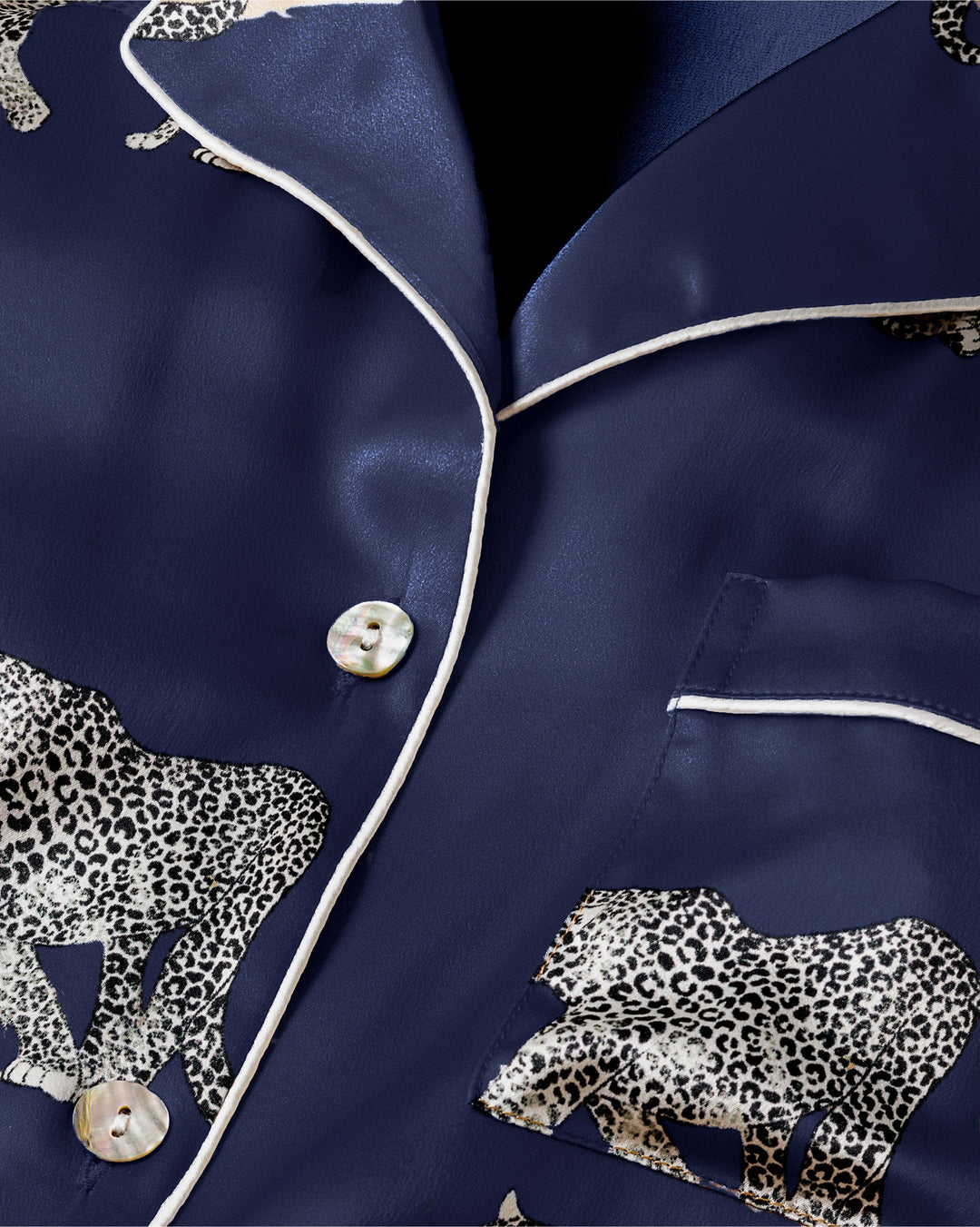 Navy satin pajama set with leopard appliqués on a dark background