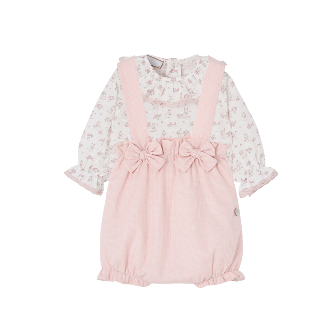 A baby girl's long-sleeve romper in light pink and white floral print, featuring solid pink shoulder straps with attached bows at the waist and a ruffled neckline.